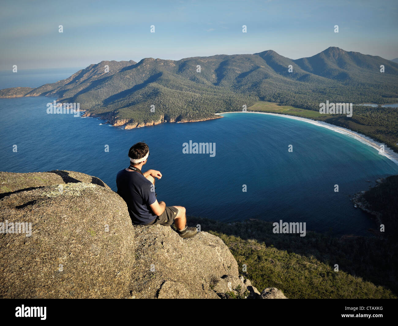 Wanderer genießt Aussicht von einem Felsen auf Mt Amos am Wineglass Bay, Strand, Freycinet National Park, Tasmanien, Australien Stockfoto