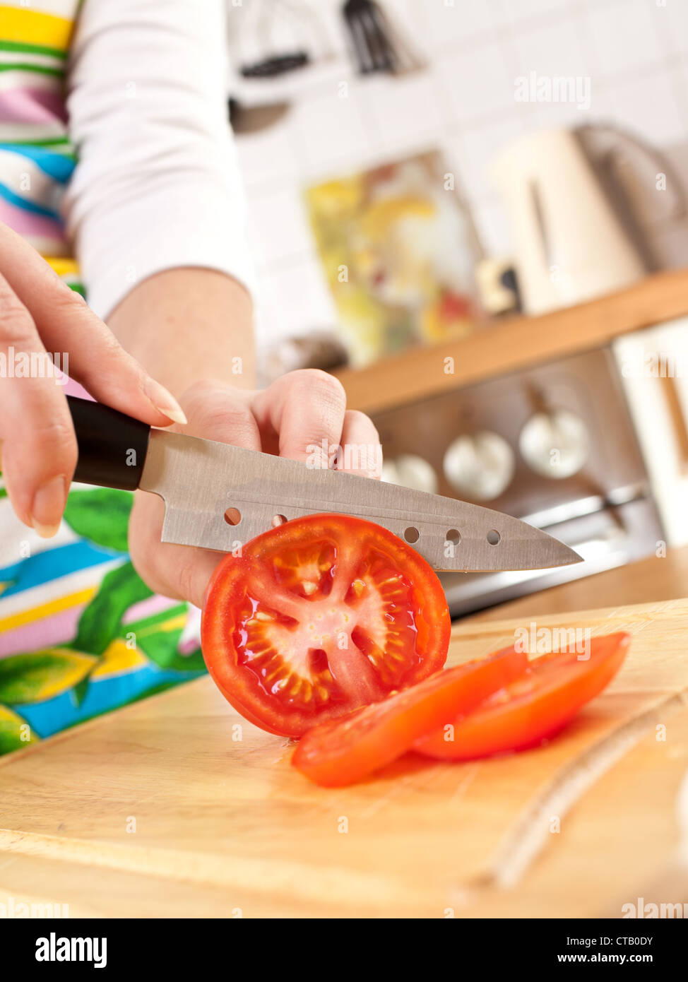Frauenhand Tomate, einem scharfen Messer schneiden. Stockfoto