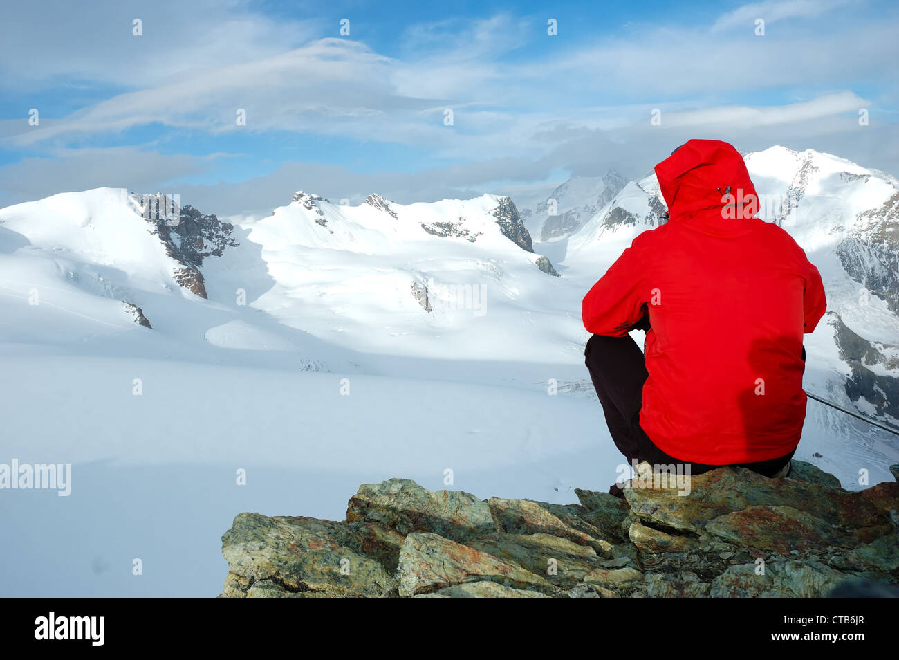 Bergsteiger sitzt auf einem Stein betrachten große Gletscher und Berge geschneit. West-Alpen, Italien. Stockfoto