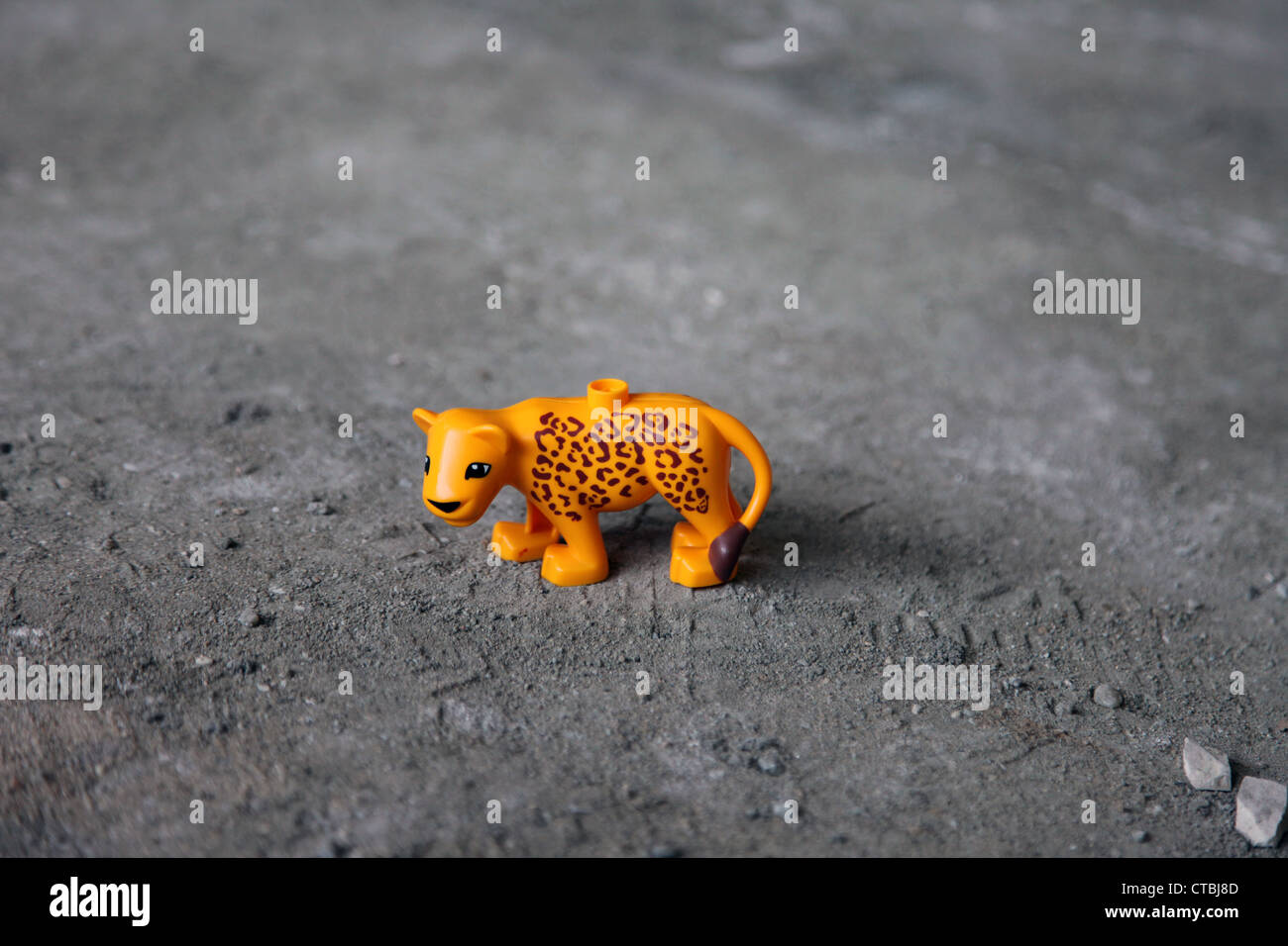 Es ist ein Foto von einem Spielzeug Kunststoff Tiger in orange Farbe, die auf dem Boden auf den Staub stehen. Es ist ein Kind kleines Spielzeug Figur einsam Stockfoto
