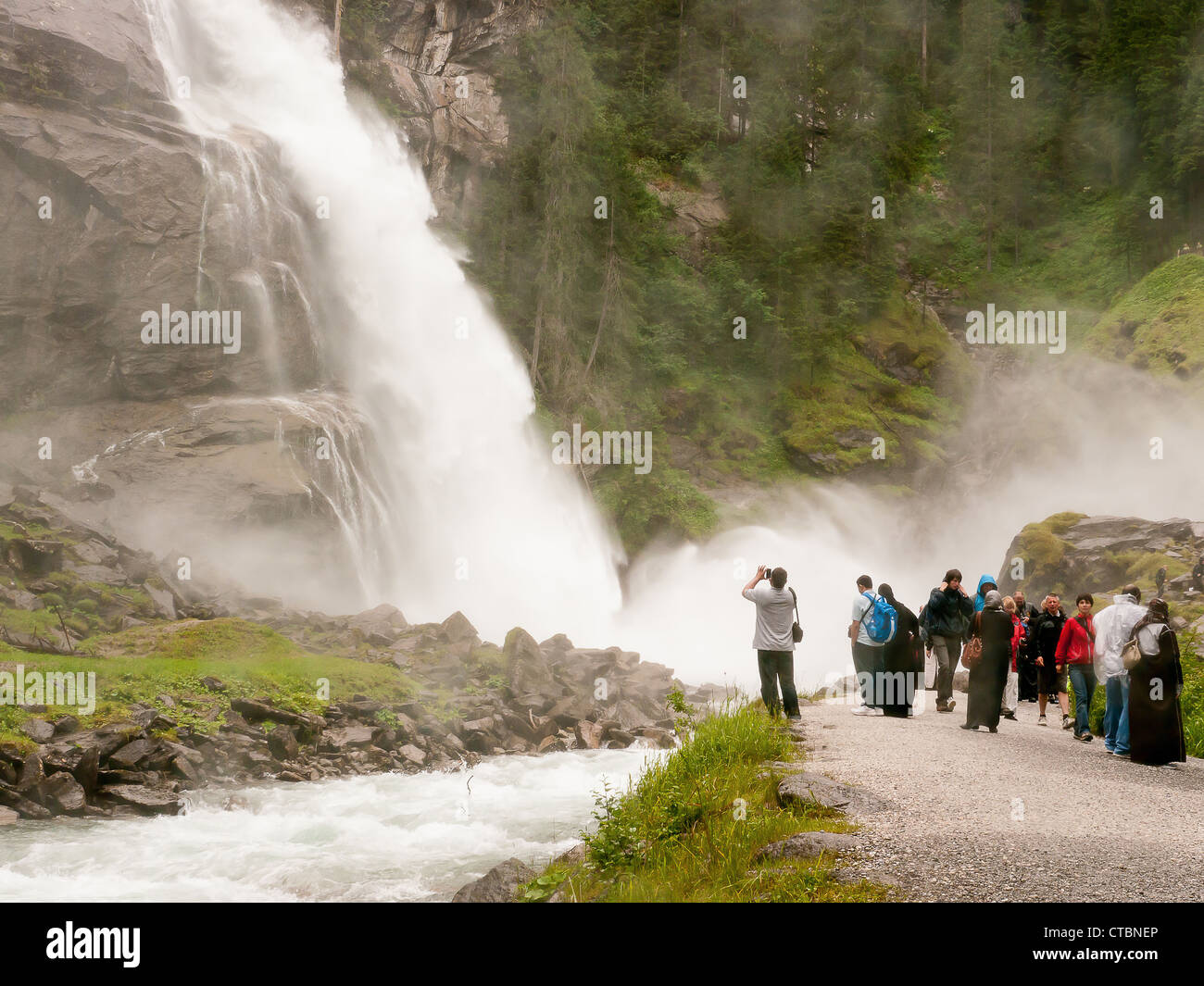 Touristen in der Gischt am Fuße der Krimmler Wasserfälle in Österreich, die höchste in Europa Stockfoto