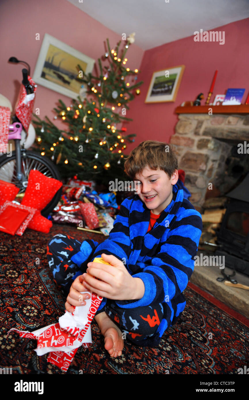 Ein elfjähriger Junge öffnet seine Strumpf am Weihnachtstag. Stockfoto