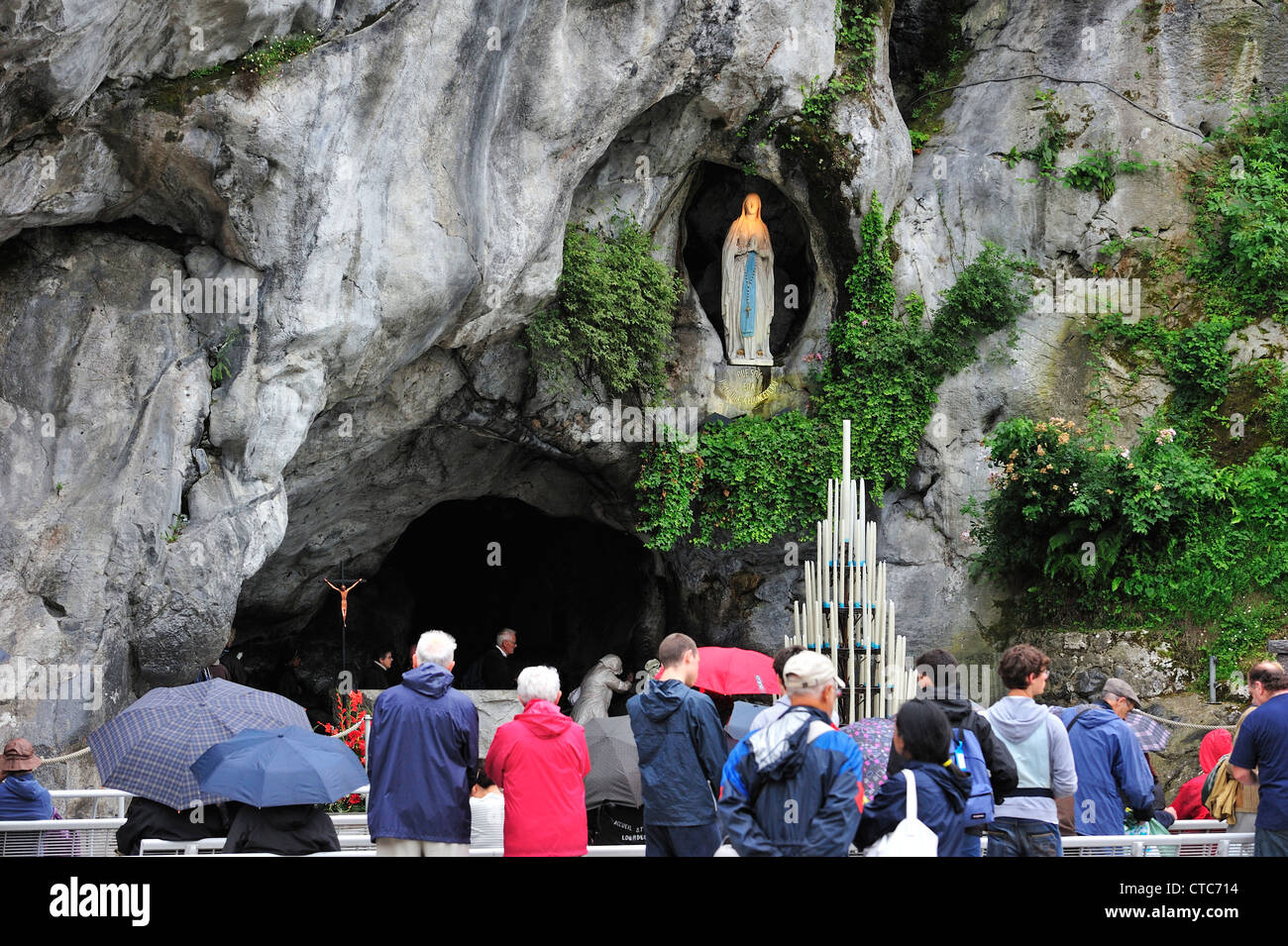 Pilger im Regen beten vor der Grotte an der Wallfahrtskirche unserer lieben Frau von Lourdes, Pyrenäen, Frankreich Stockfoto