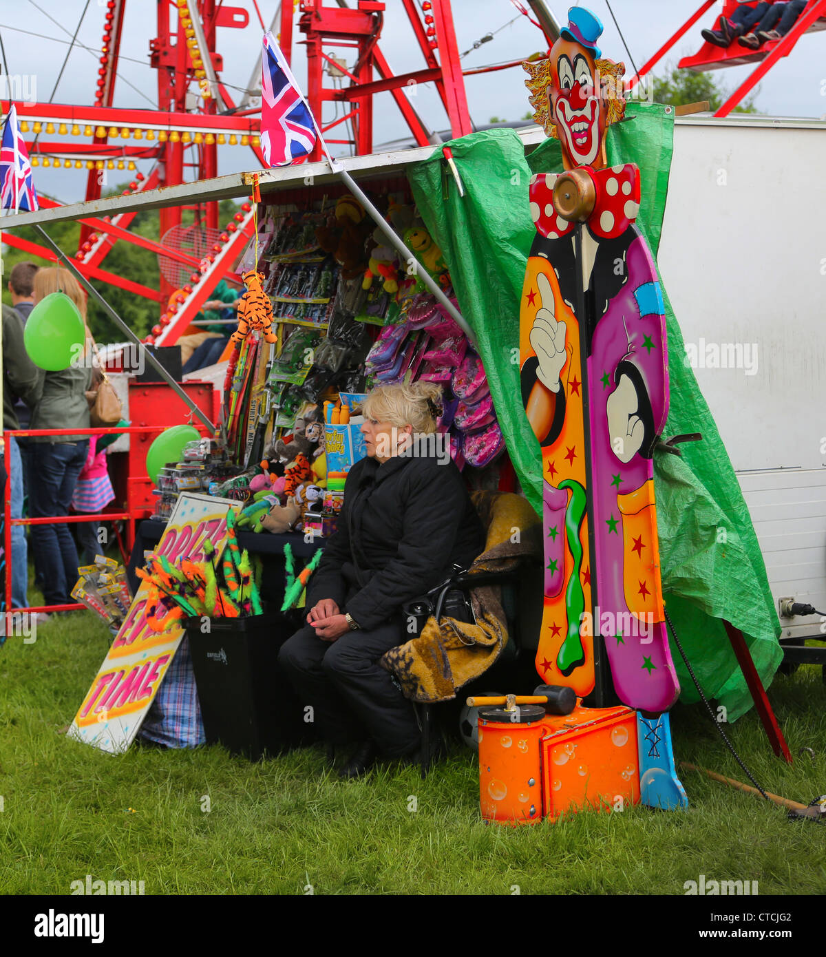 Frau sitzt von hohen Stürmer testen Ihre Stärke Stand auf Cheam Dorf Fair Surrey England Stockfoto