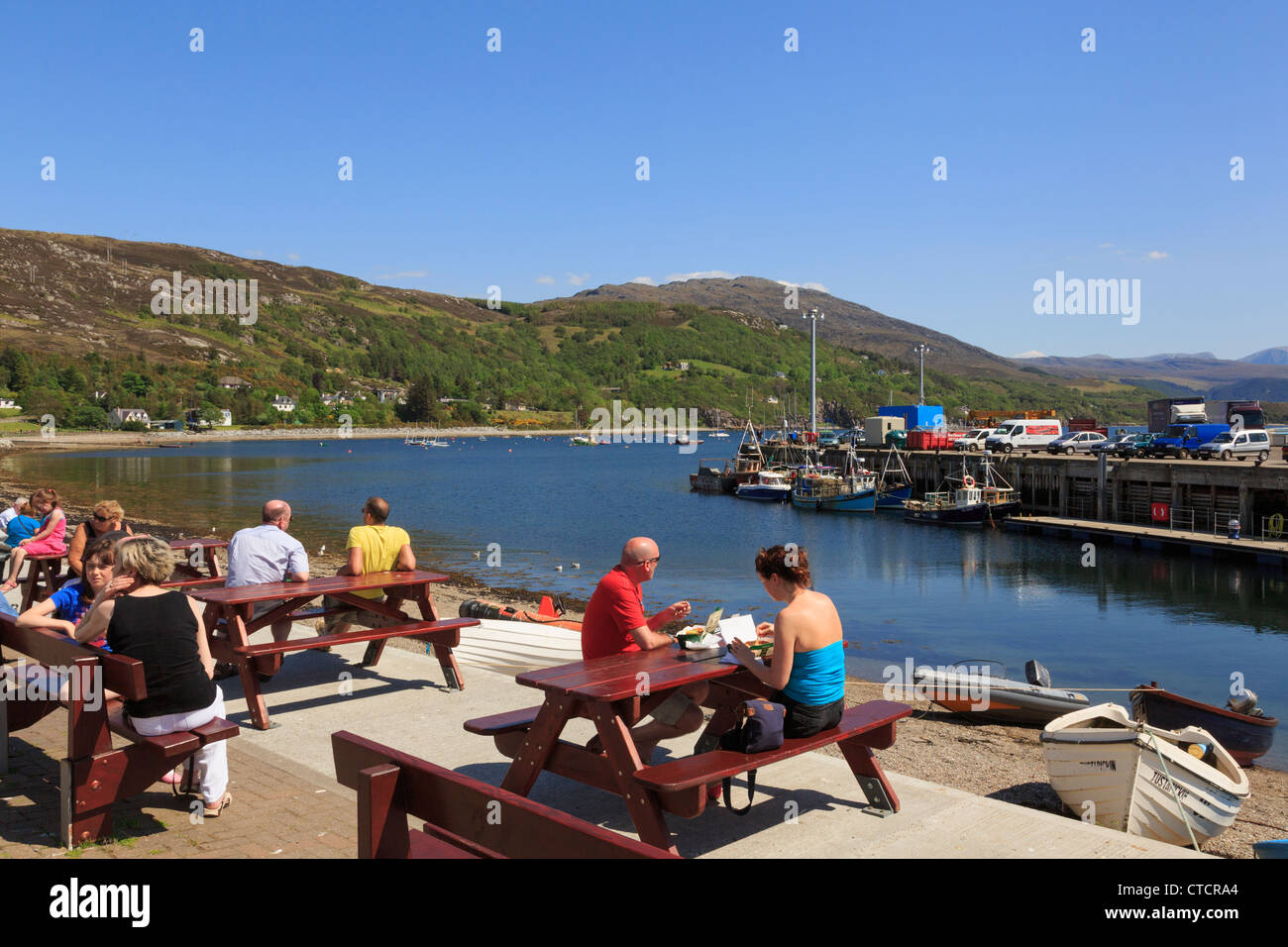 Menschen an Tischen sitzen auf Meer mit Loch Broom Fischerhafen auf Northwest Highlands Küste im Sommer Saison. Ullapool Schottland Großbritannien Stockfoto