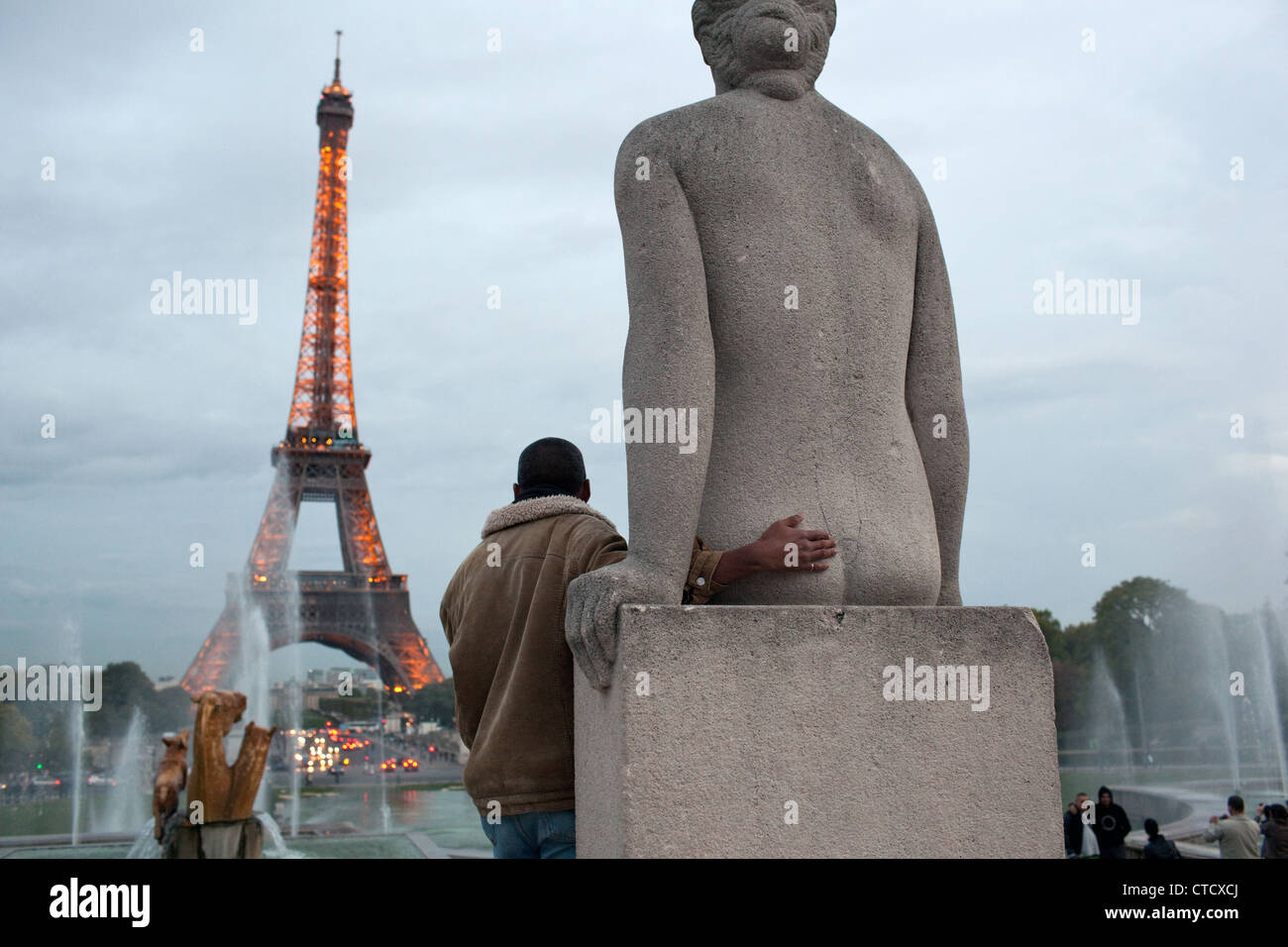 Eine humorvolle Szene, wenn ein Mann für ein Foto mit einer Statue auf Trocadero nahe des Eiffelturms in Paris, Frankreich darstellt. Stockfoto