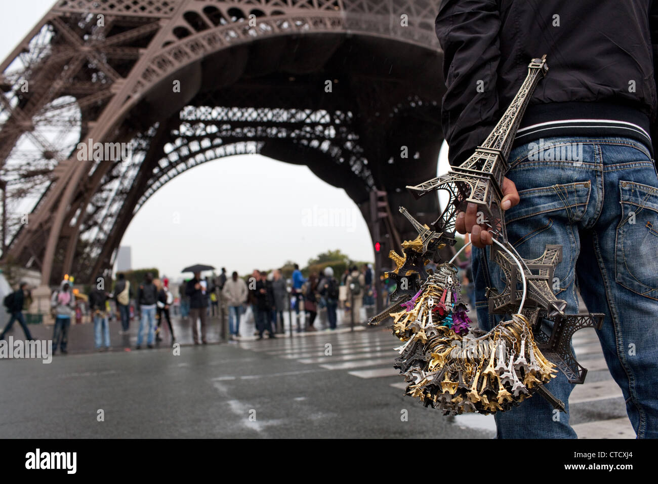Ein Mann, der illegal mit Eiffelturm Souvenirs vor dem Turm (aus Trocadero) nahe dem Eiffelturm in Paris, Frankreich. Stockfoto