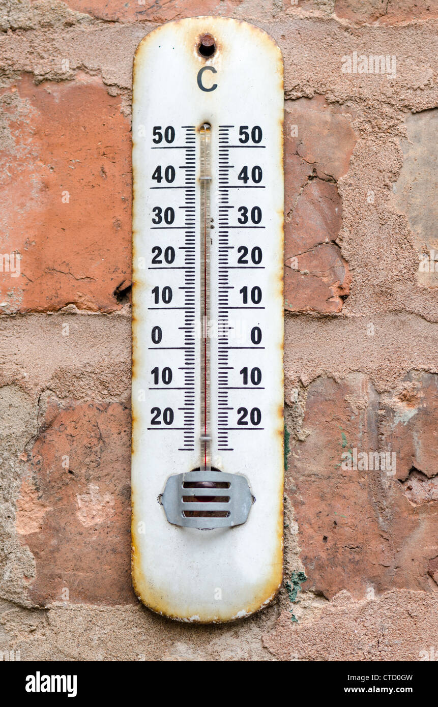 Alte rostige Thermometer hing im Freien auf einer roten Backsteinmauer Stockfoto