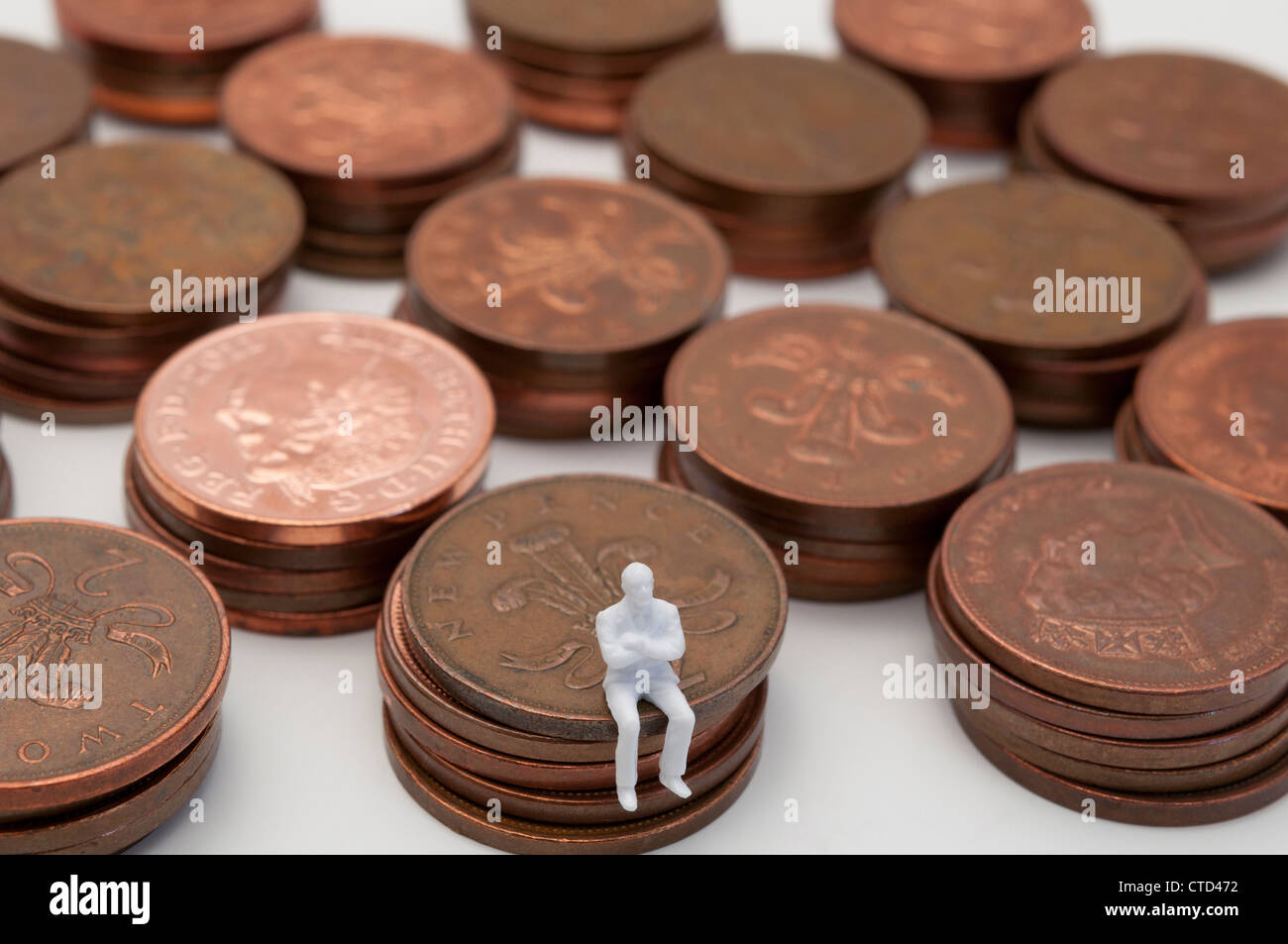 Besorgt Figur sitzt auf Stapel von Kupfer zwei Pence-Stücke Stockfoto