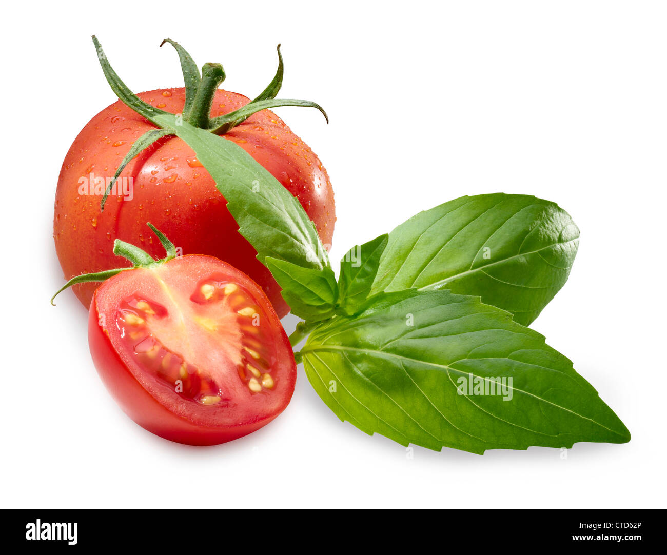 Ganze Tomaten mit einer halben Tomate vor und drei Blätter Basilikum gegen weiß. Stockfoto