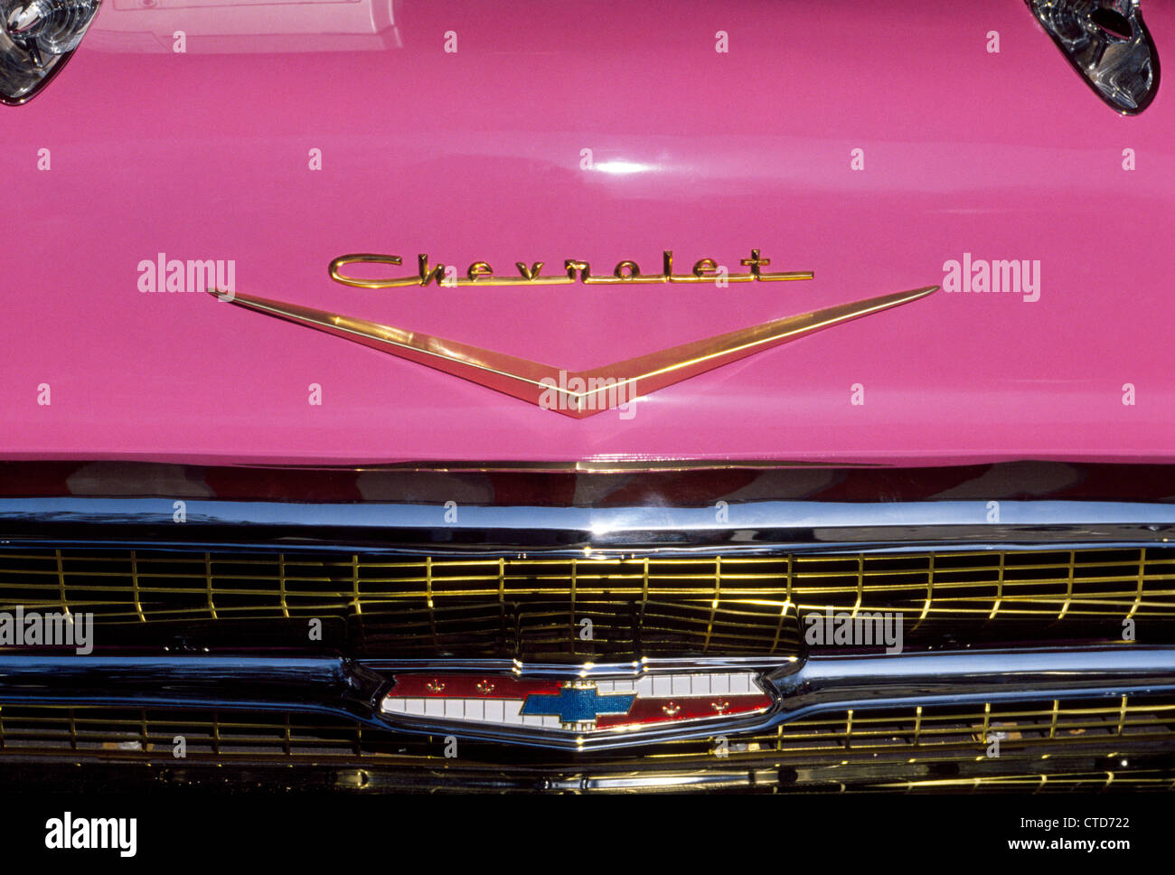 Eine Nahaufnahme der rosa Automobil-Haube (Mütze) mit den Insignien und Markenname eines amerikanischen Oldtimers, das Modell von 1957 Chevrolet (Chevy) Bel Air. Stockfoto
