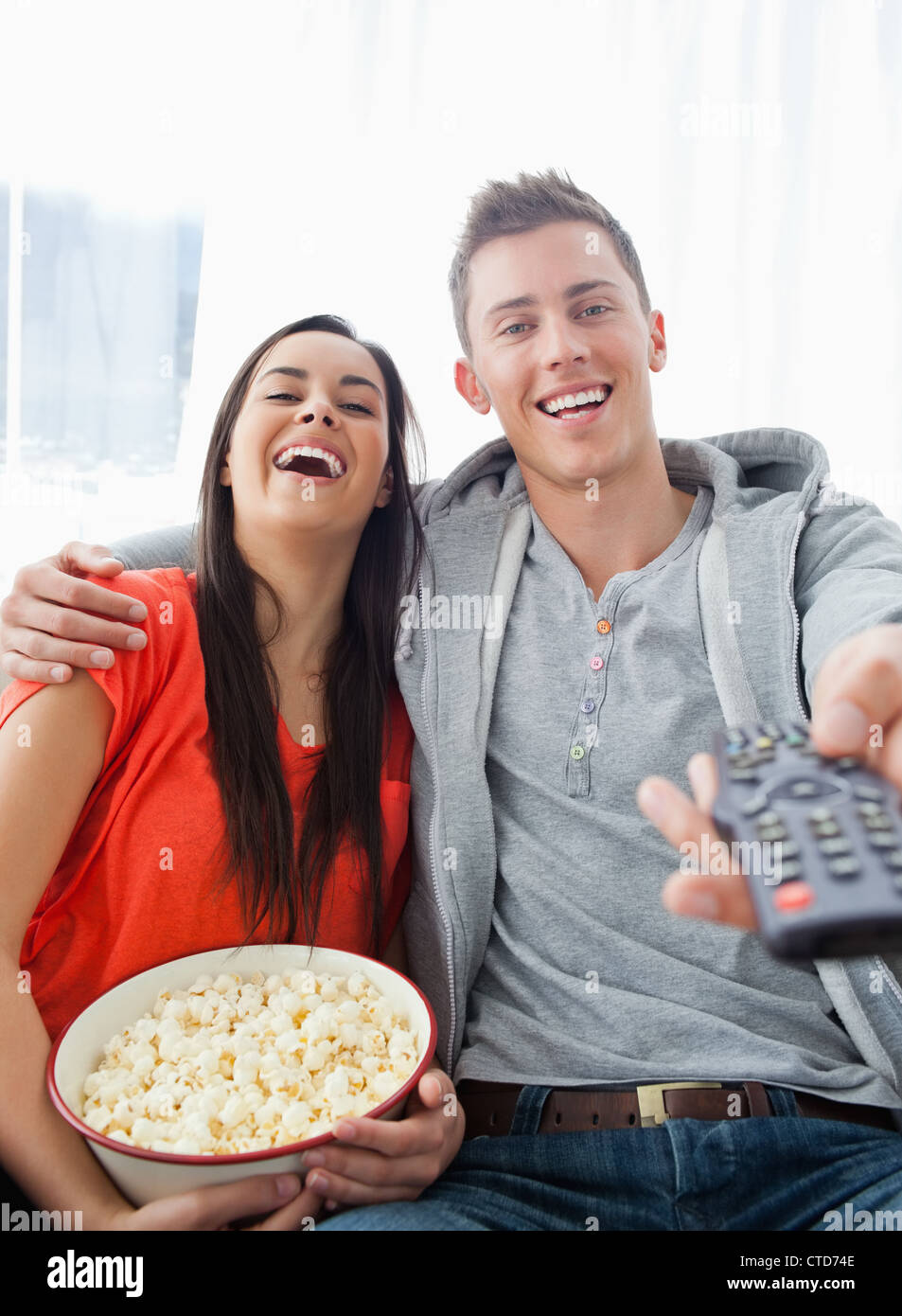 Ein lachendes paar sitzen auf der Couch mit Popcorn, wie sie Fernsehen Stockfoto