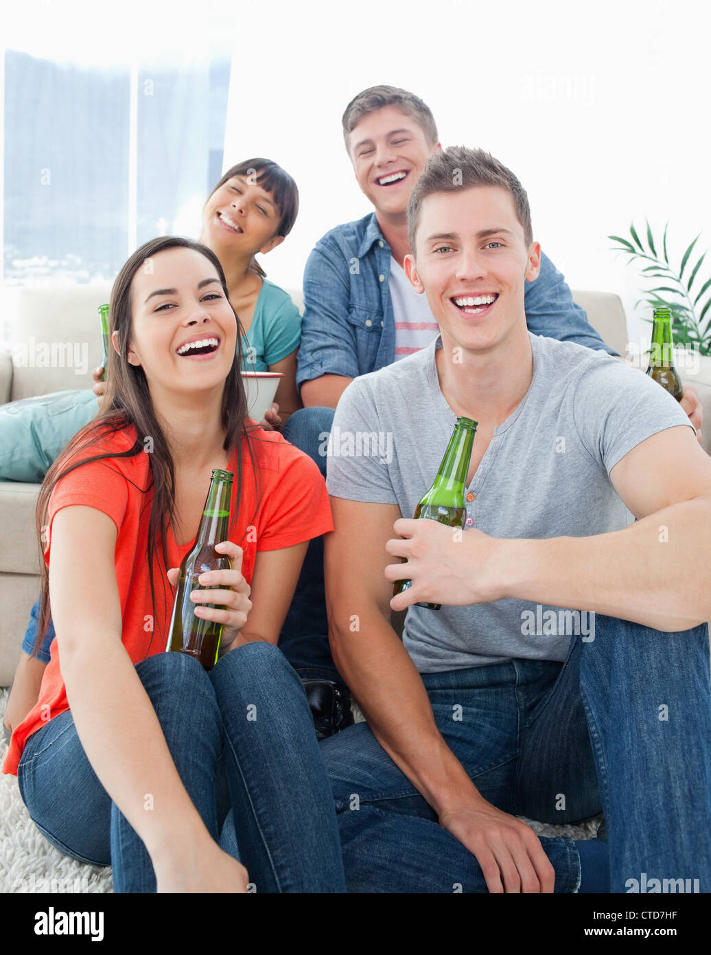 Ein Lachen Gruppe sitzen auf der Couch und den Boden mit Bier in der hand Stockfoto