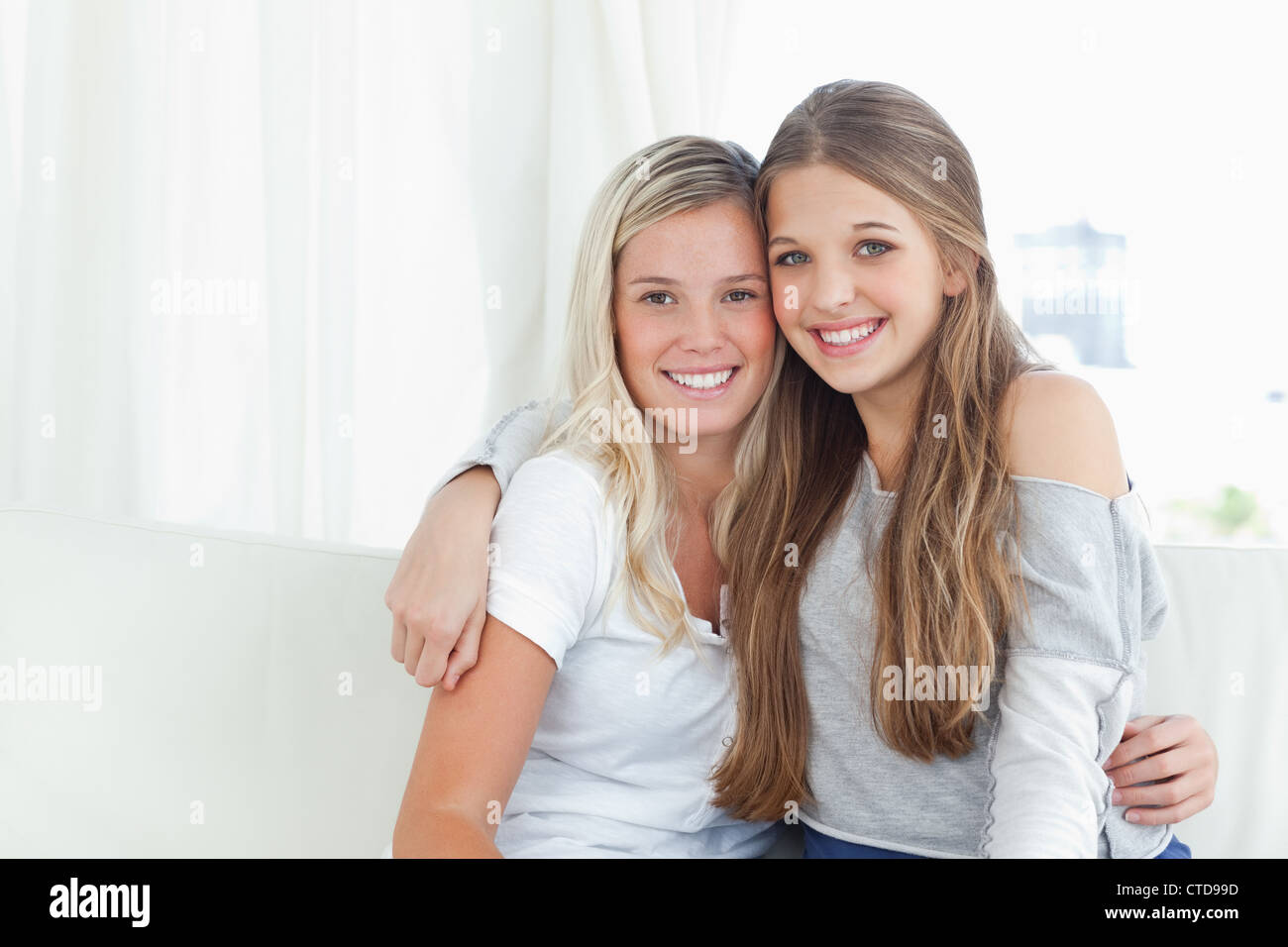 Ein paar Schwestern umarmen einander, wie sie in die Kamera schauen Stockfoto
