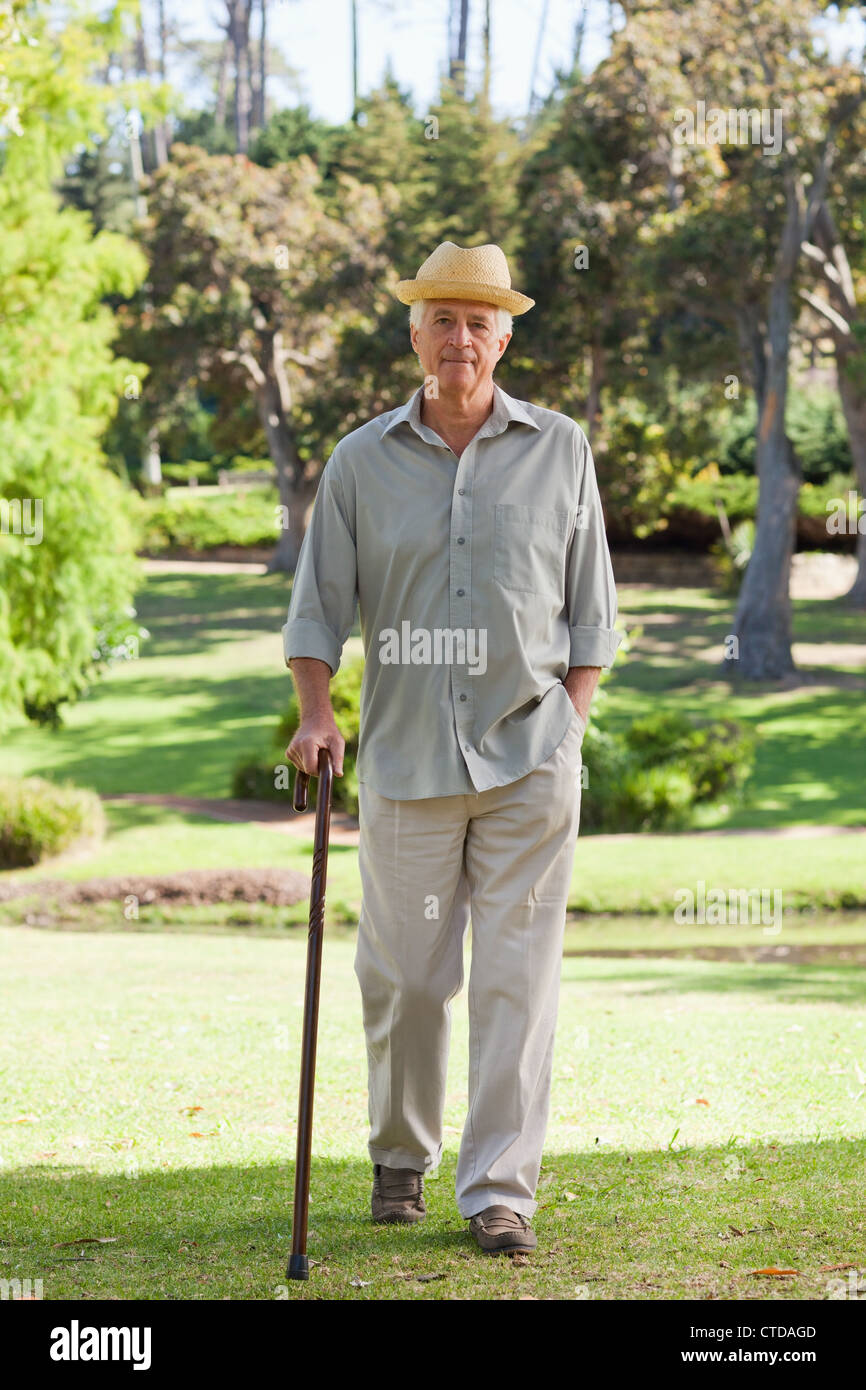 Alter Mann zu Fuß in Richtung Kamera mit Gehstock Stockfoto