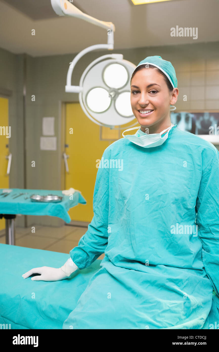 Krankenschwester, lächelnd, während Sie auf dem OP-Tisch sitzen Stockfoto