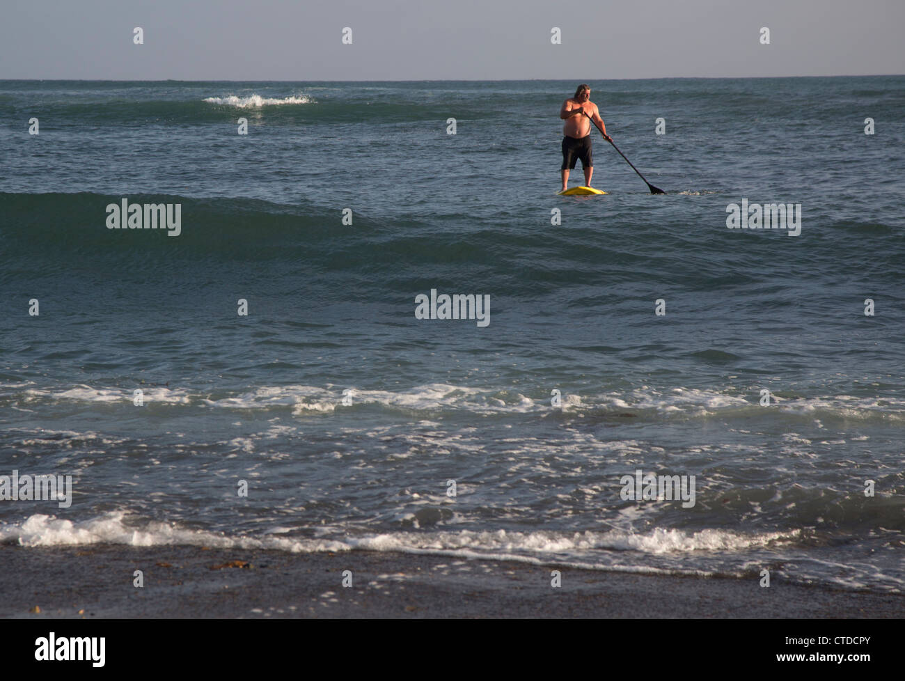 Ein Mann paddelt ein Surfbrett am San Onofre Surf Beach Stockfoto Ein Mann paddelt ein Surfbrett am San Onofre Surf Beach Stockfoto
