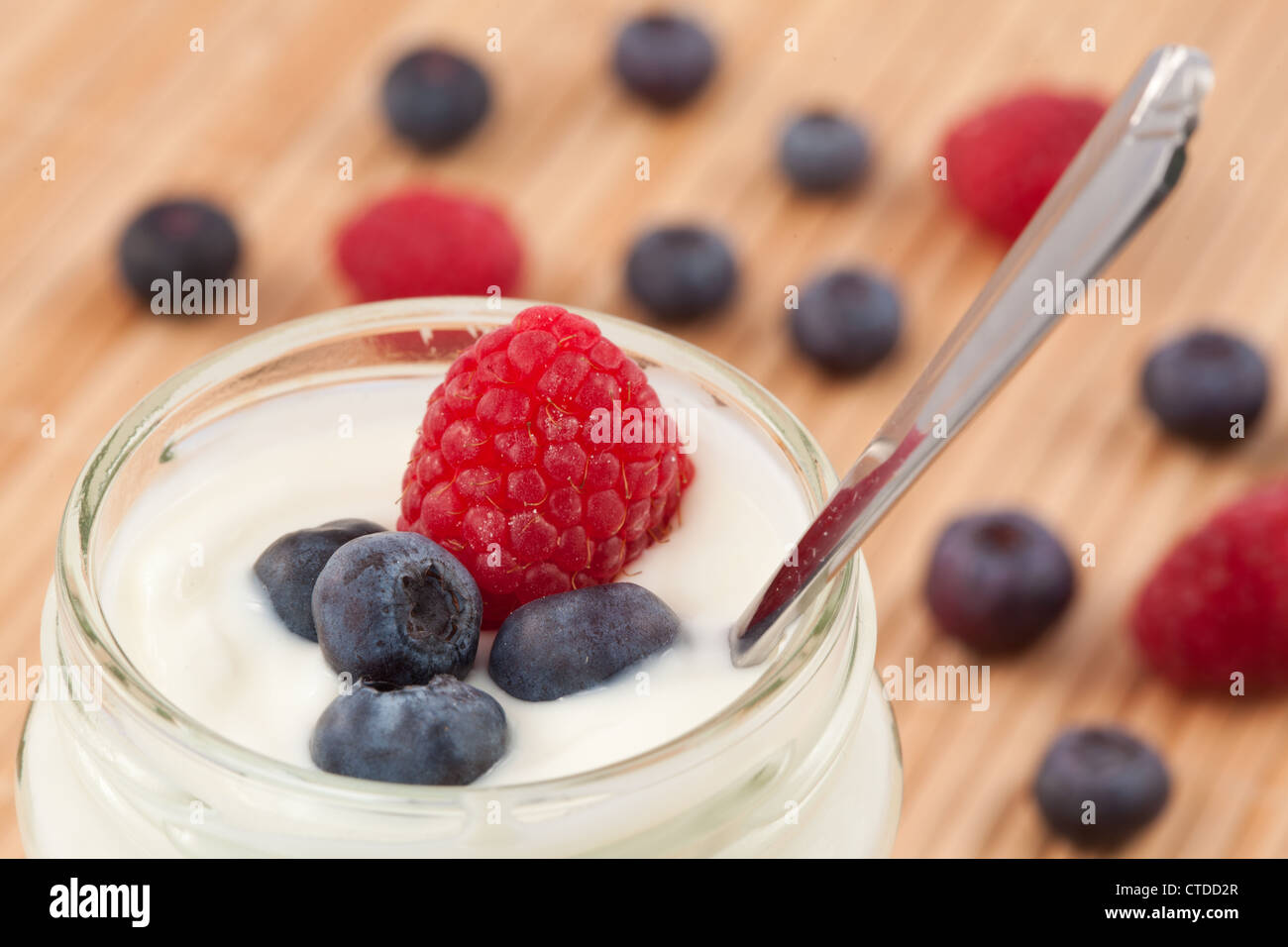 Nahaufnahme von einem Topf Joghurt mit Heidelbeeren und Himbeeren Stockfoto