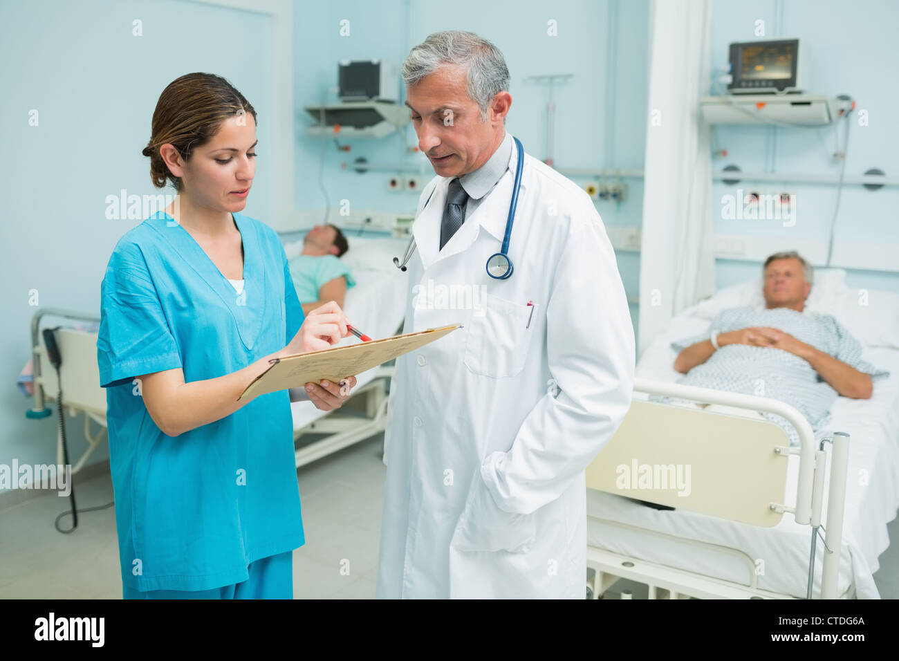 Arzt und Krankenschwester lächelnden Blick auf medizinische Tabelle in einem Krankenhaus Stockfoto