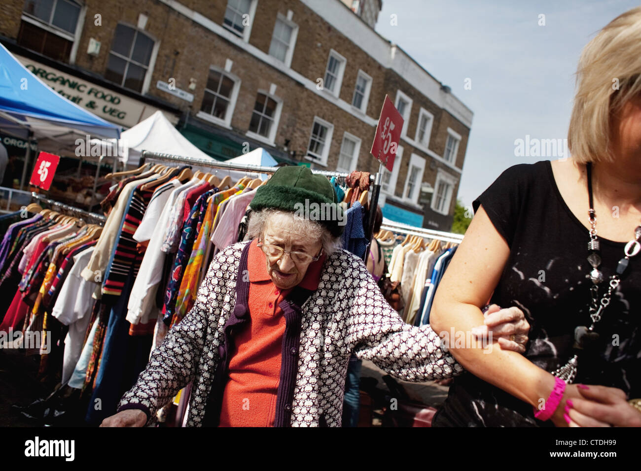 Eine alte Frau ist durch den quirligen Markt geholfen. Broadway Market in Hackney, East London ist ein sehr beliebter Straßenmarkt geworden. Stockfoto