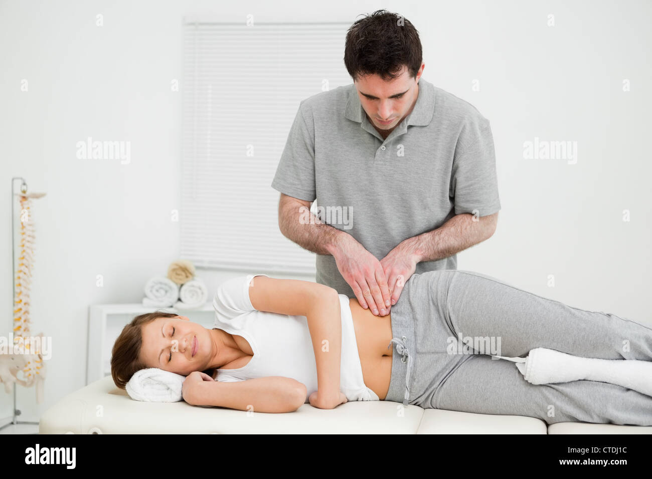 Friedliche Frau massiert auf ihrer Hüfte durch einen Arzt Stockfoto