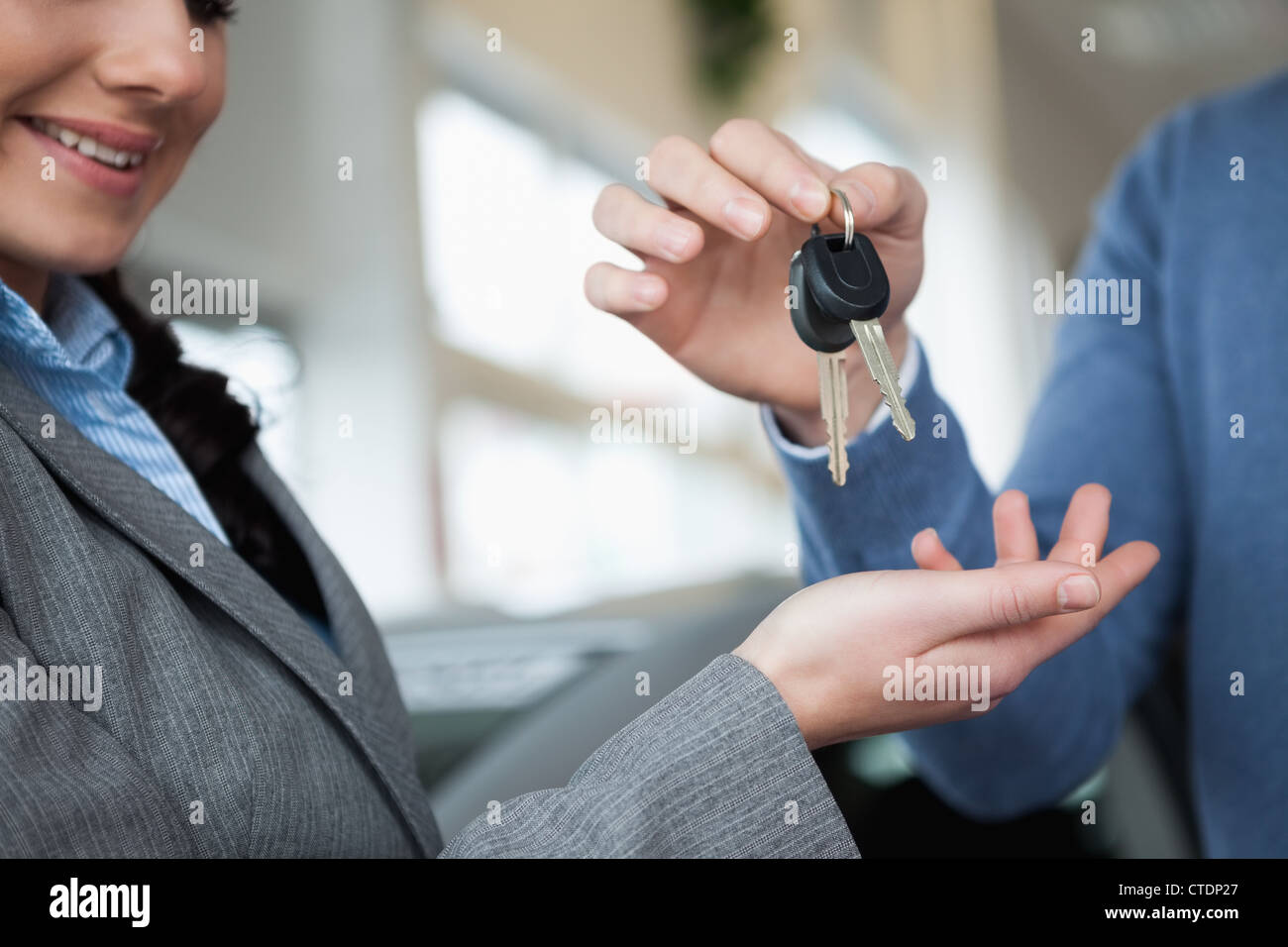 Lächelnde Frau empfangende Schlüssel aus einer hand Stockfoto