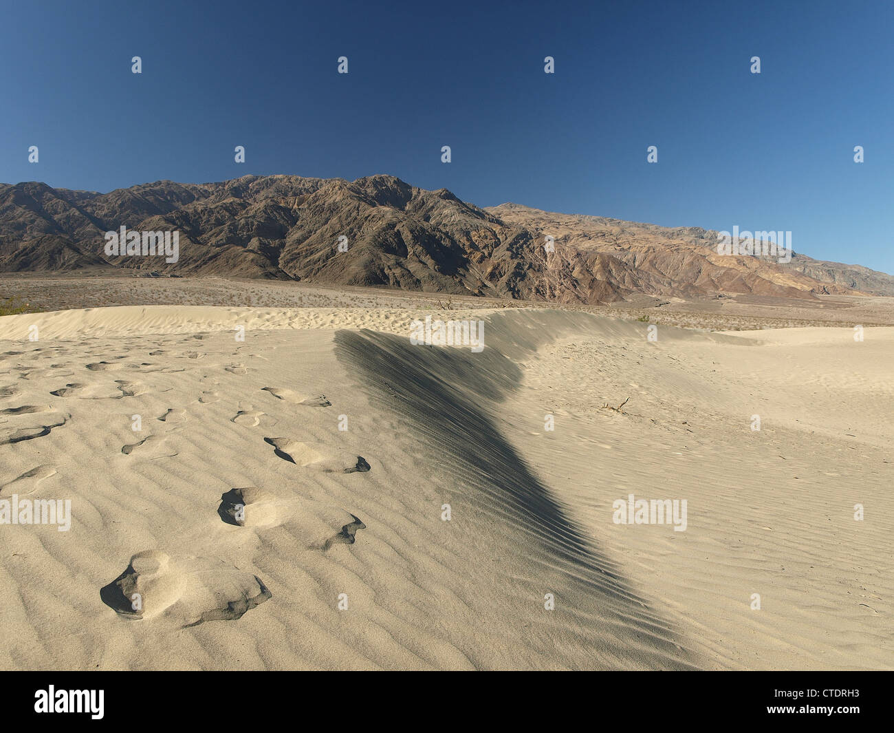Fußabdrücke in Sanddünen im Death Valley, eine Wüste und Berge Landschaft im Hintergrund. Stockfoto