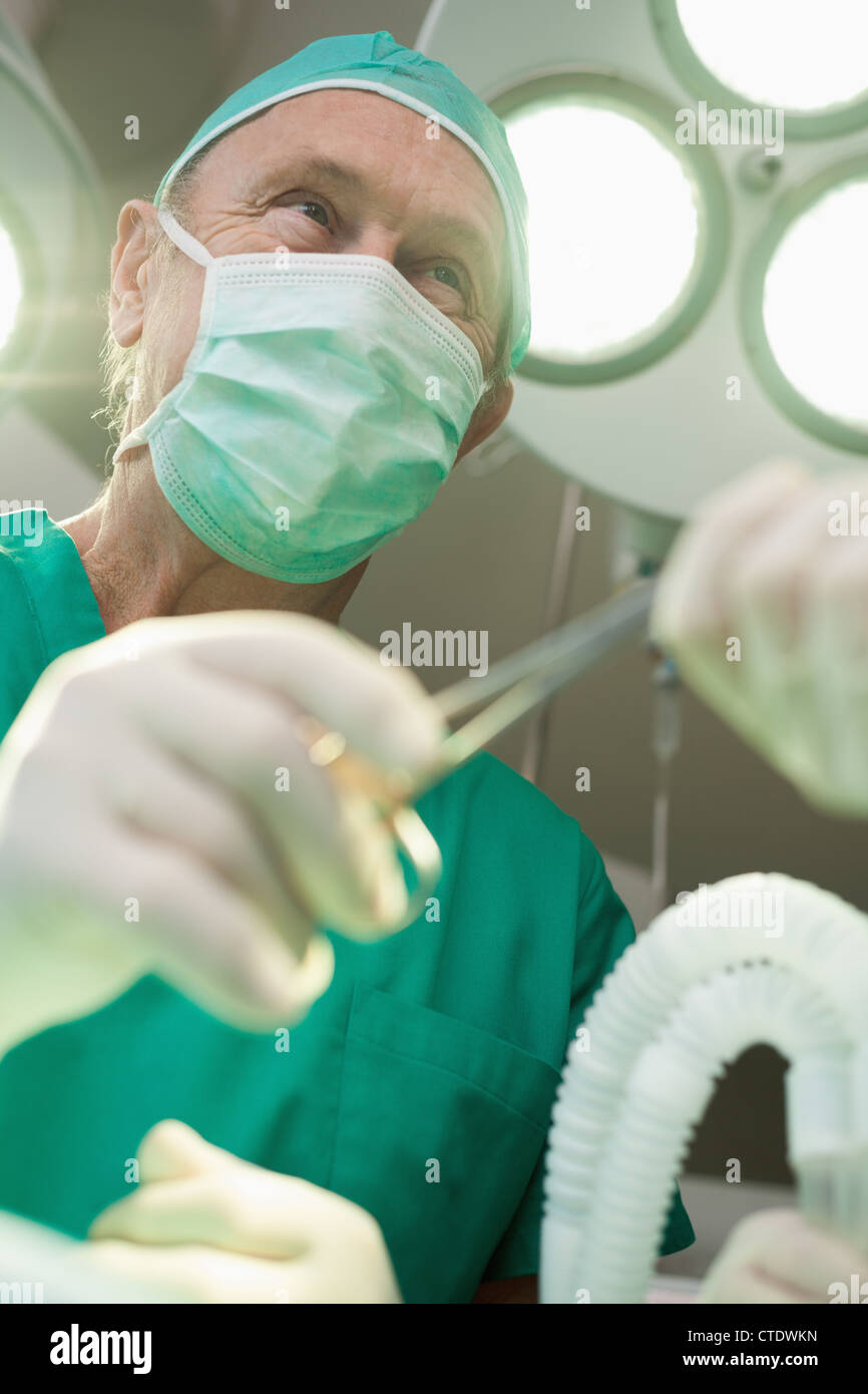Chirurg lächelt, als er eine chirurgische Schere nimmt Stockfoto