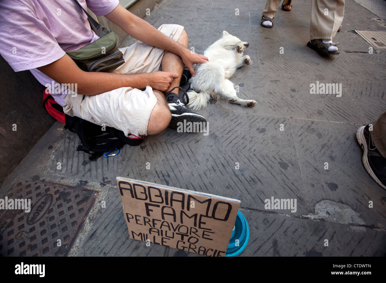 Bettler mit Hund auf Straße in Zentral-Florenz, Italien - Schild sagt hungrig, bitte helfen. Stockfoto