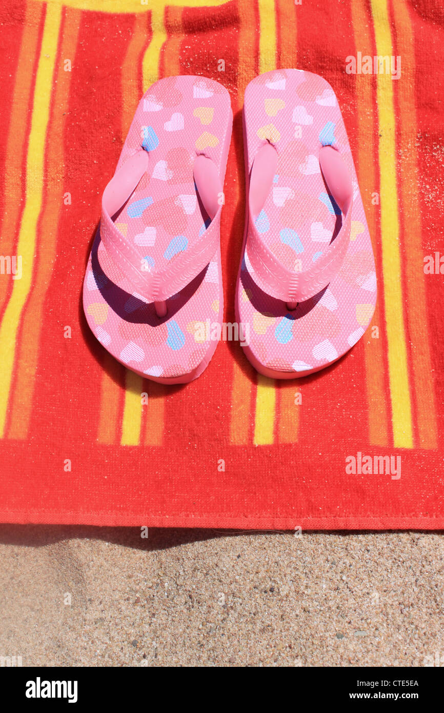 Kinder flip-flop Sandalen auf einem bunten Handtuch am Strand Stockfoto