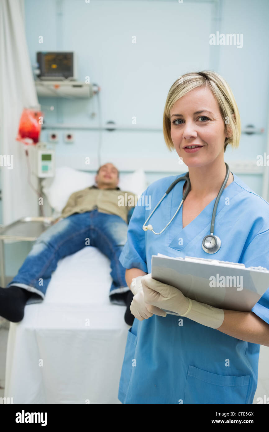 Neben einem männlichen Patienten ein Klemmbrett mit gedrückter Krankenschwester Stockfoto