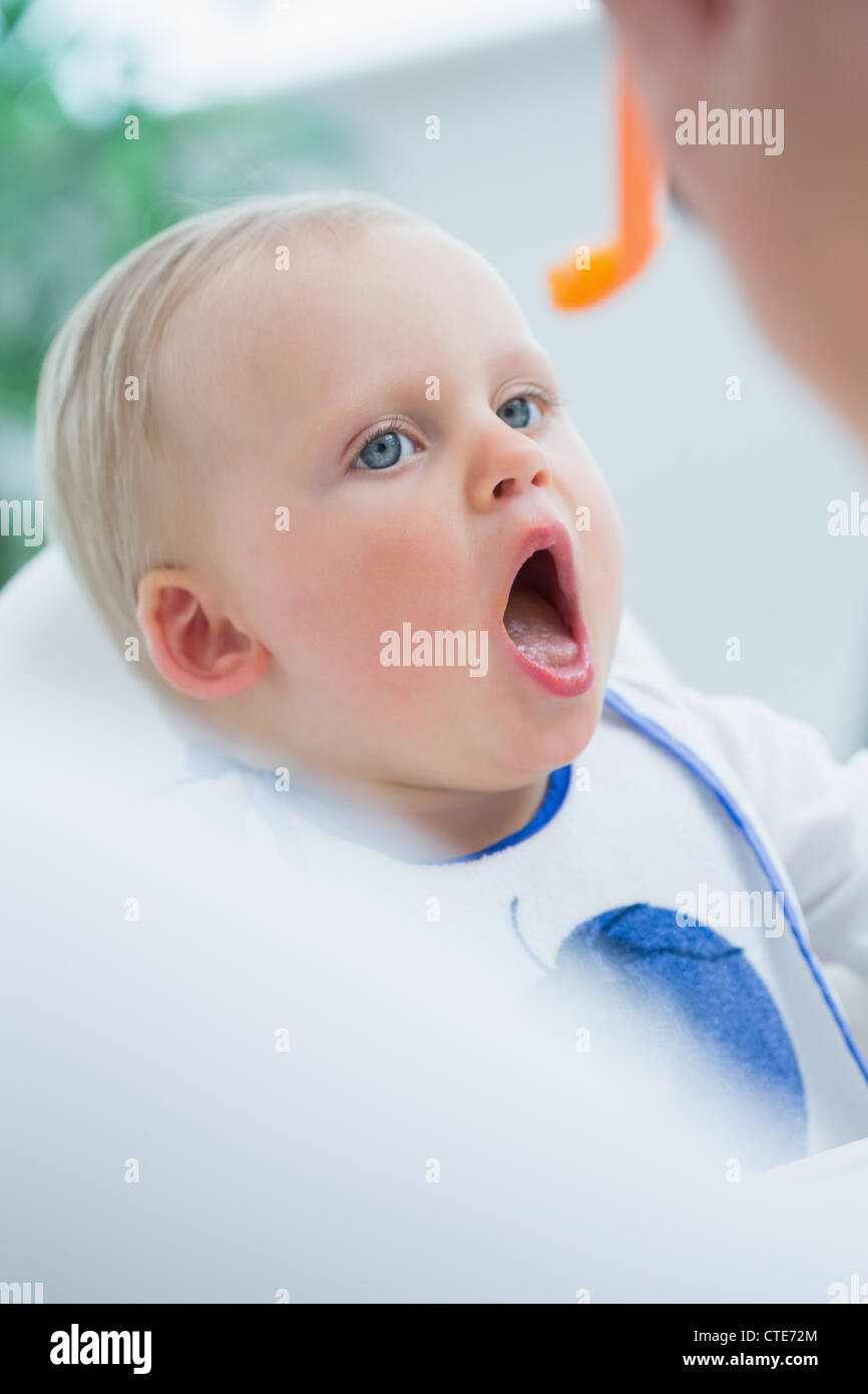 Baby auf einem hohen Stuhl mit geöffneten Mund Stockfoto