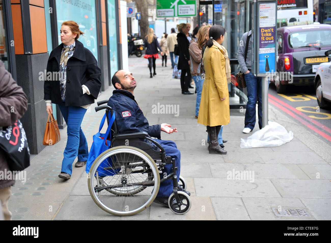 Ein behinderter Mann bittet aus seinem Rollstuhl in Knightsbridge London. Stockfoto