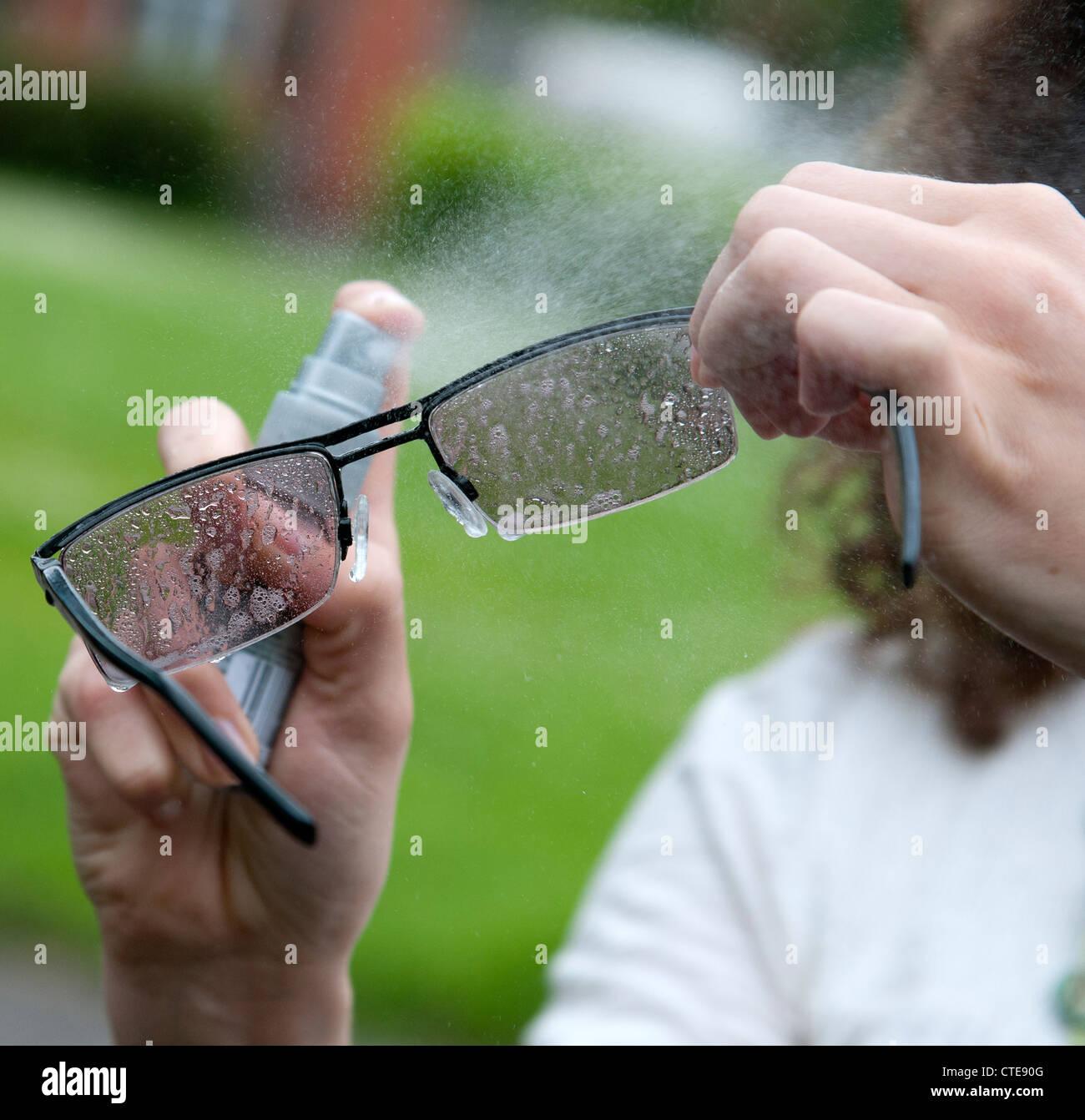 Reinigung von Brillen mit einem Spray auf cleaner Stockfoto