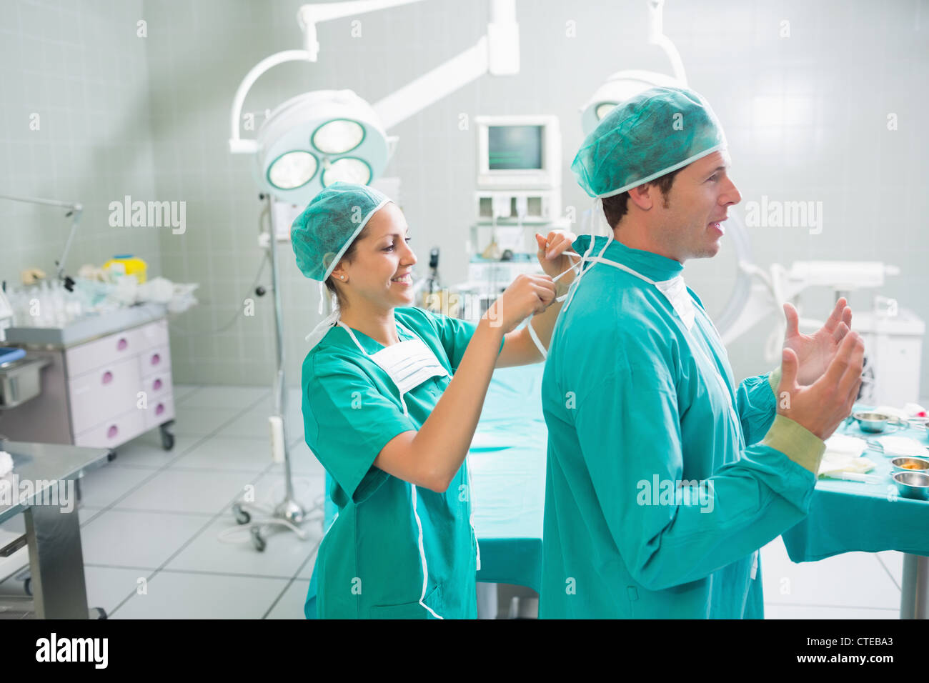 Krankenschwester, die Befestigung der chirurgischen Uniform eines Chirurgen Stockfoto