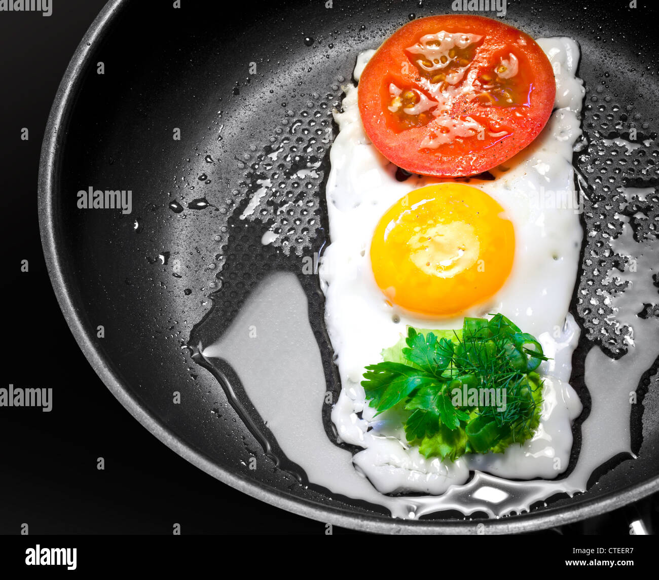 Originalthemas Frühstück. Spiegeleier mit Tomaten und grünen in Form der Ampel in einer Pfanne erhitzen Stockfoto