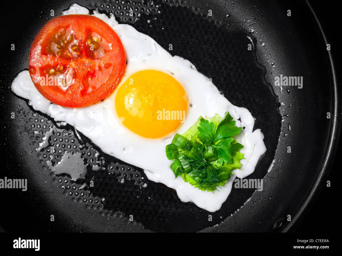 Originalthemas Frühstück. Spiegeleier mit Tomaten und grünen in Form der Ampel in einer Pfanne erhitzen Stockfoto