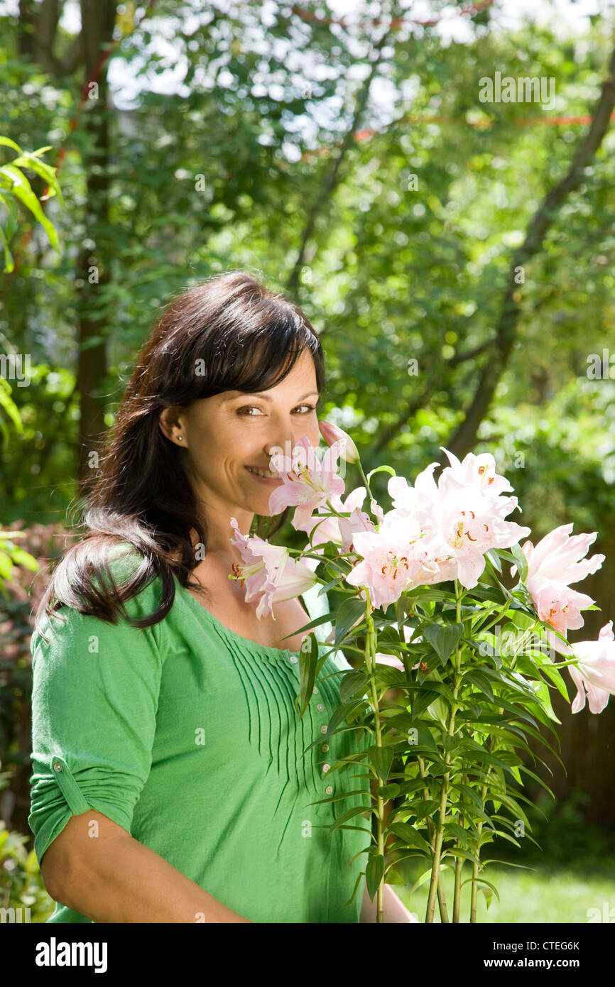 Frau im Garten tragen eingemachte Lilien Stockfoto