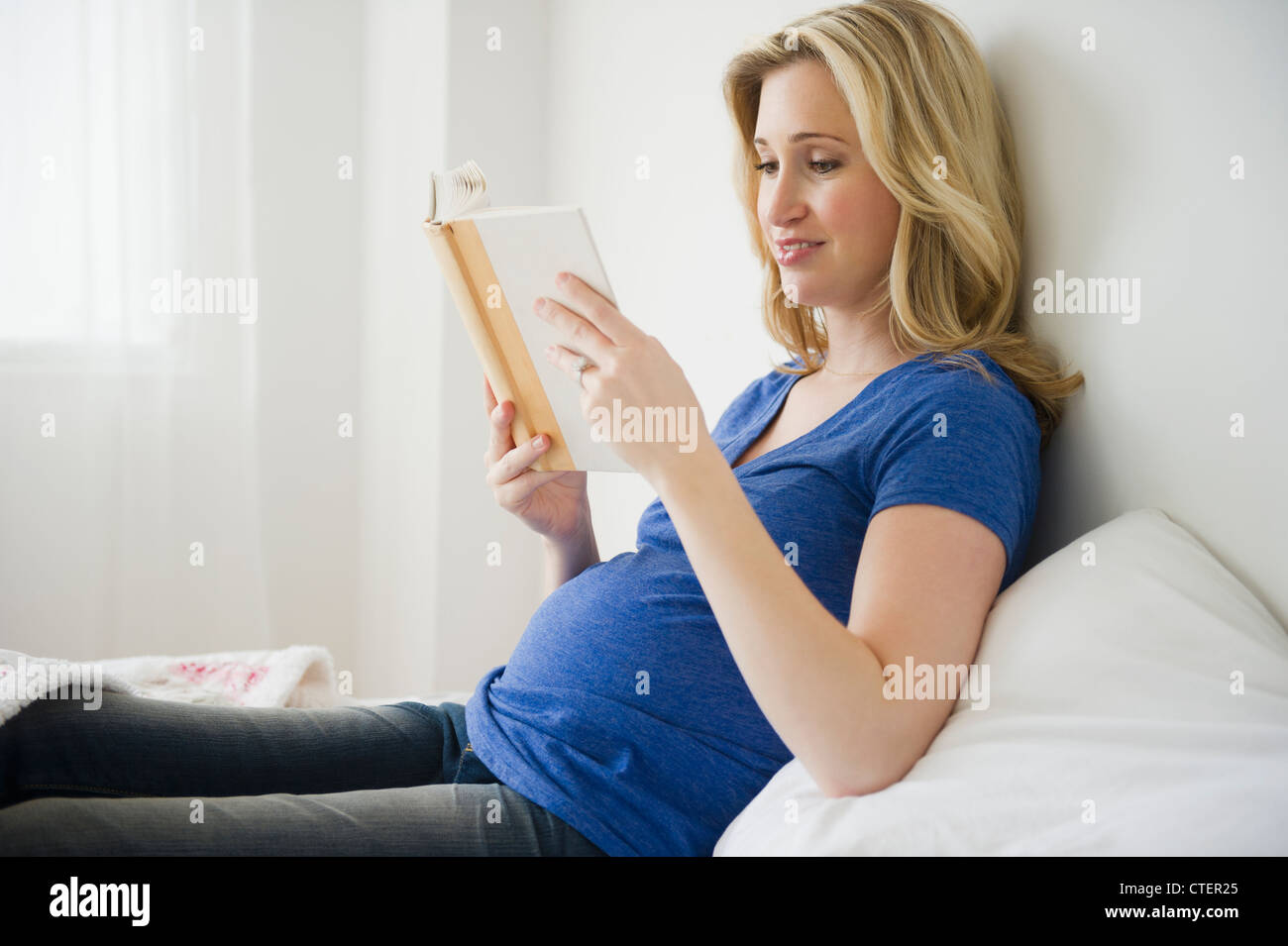 USA, New Jersey, Jersey City, schwangere Frau Lesebuch im Bett Stockfoto