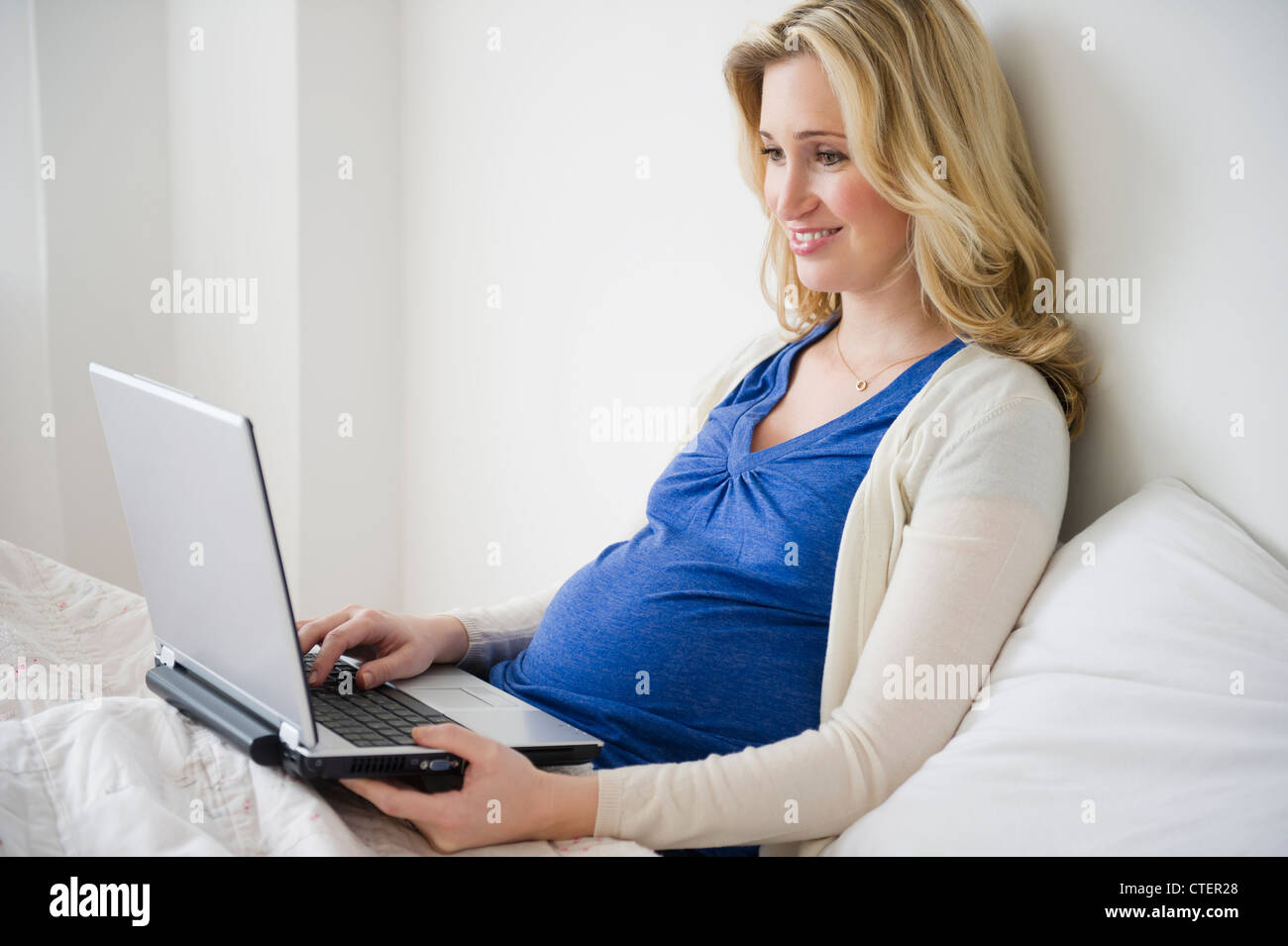 USA, New Jersey, Jersey City, schwangere Frau mit Laptop im Bett Stockfoto