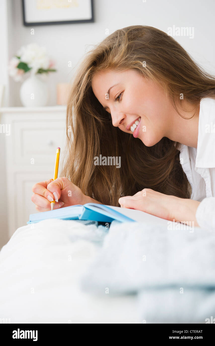 USA, New Jersey, Jersey City, Frau auf Bett liegend und Tagebuch zu schreiben Stockfoto