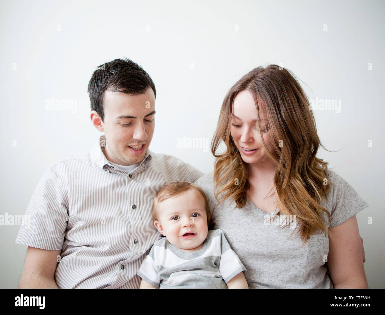 Junges Paar mit Baby Boy (6-11 Monate) sitzt auf dem sofa Stockfoto