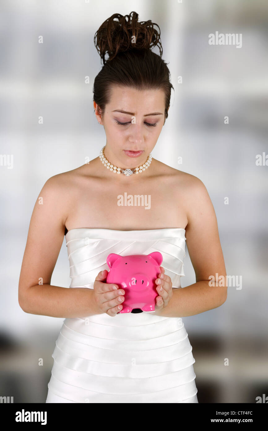Frau in einem Brautkleid mit Sparschwein Stockfoto