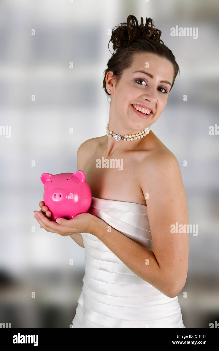 Frau in einem Brautkleid mit Sparschwein Stockfoto
