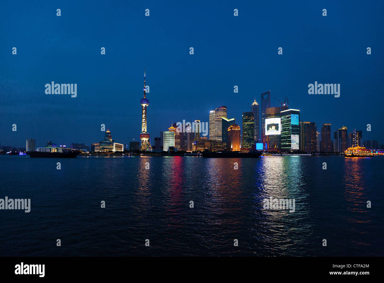 Shanghai-Wolkenkratzer in der Nähe von Wasser in der Nacht mit Spiegel Stockfoto