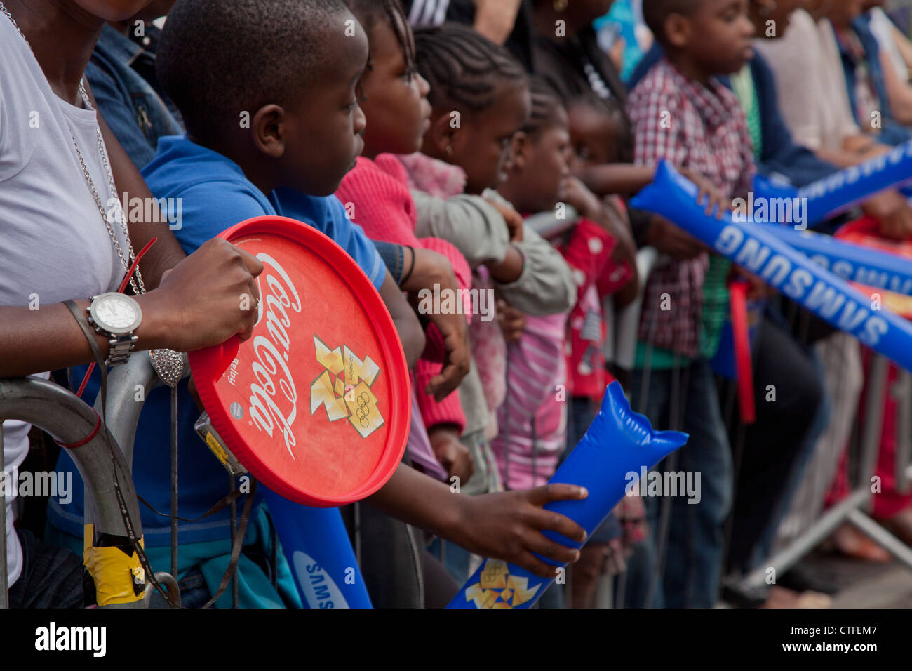 Kinder und Jugendliche mit Geschenken von Sponsoren warten auf London 2012 Olympische Fackel in Hackney, UK Stockfoto