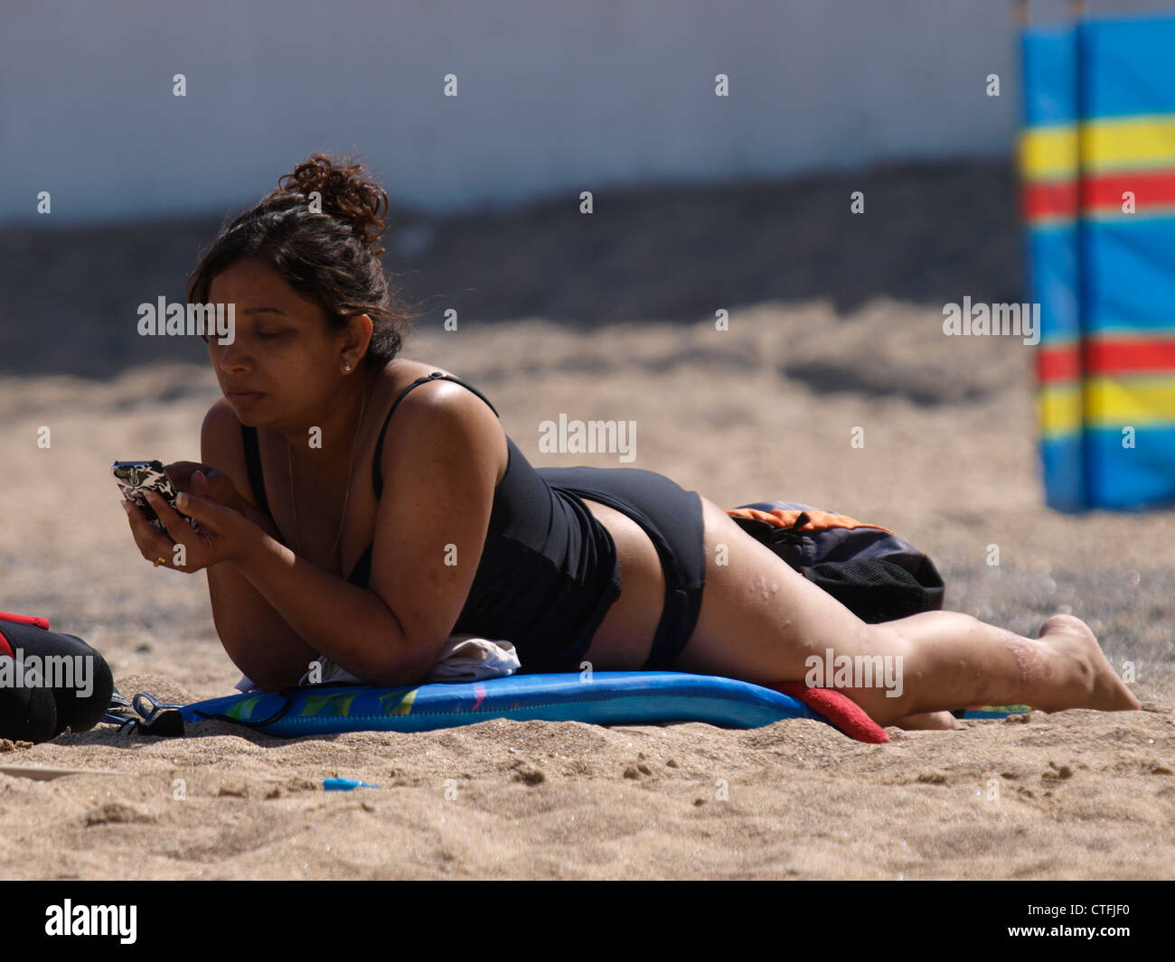 Asiatische Frau mit Telefon am Strand, Newquay, Cornwall, UK Stockfoto