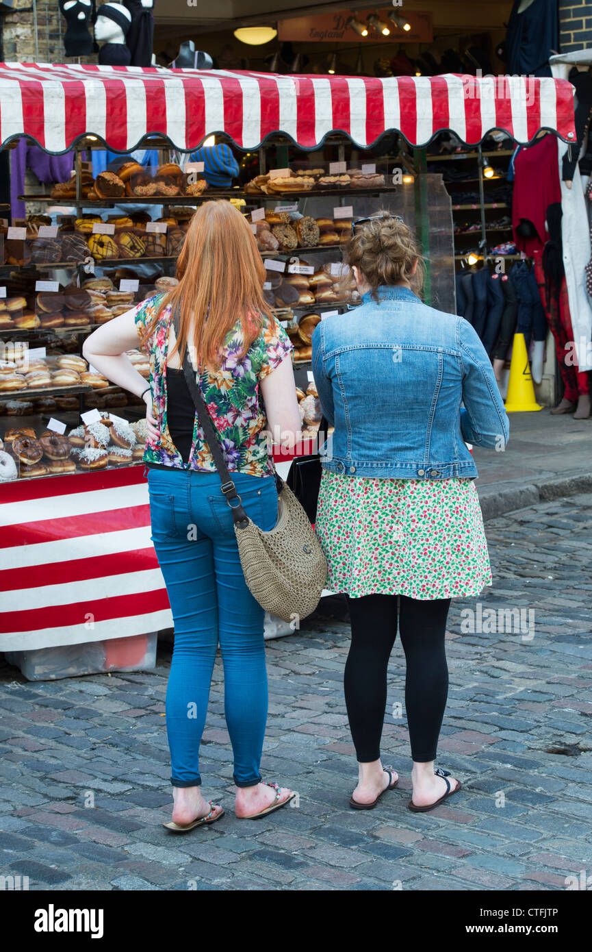 Zwei Mädchen Donuts auf einen Donut-Stand zu betrachten. Camden. London Stockfoto