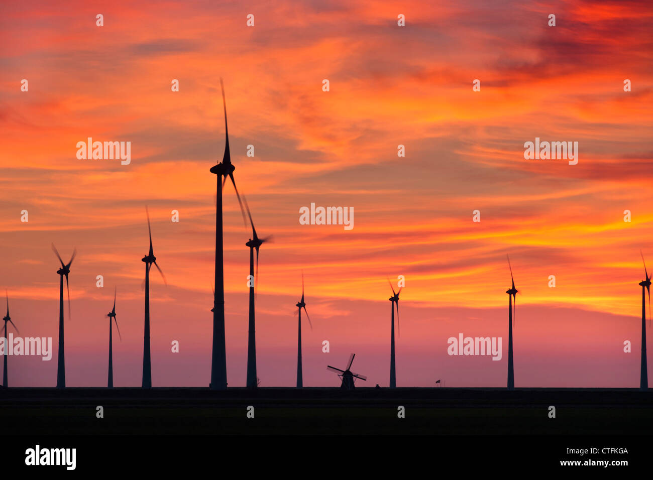 Emsmündung, Eemshaven, Windkraftanlagen und traditionelle Windmühle. Sonnenuntergang. Stockfoto