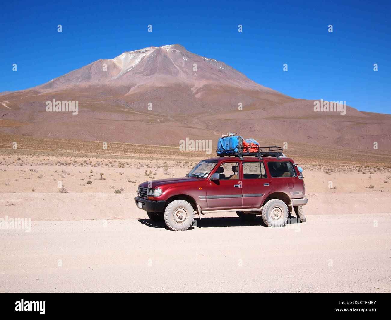 Touristischen Allradfahrzeug für mehrere touristische Tagestour in der Atacama-Wüste in Bolivien vor einem Vulkan verwendet. Stockfoto